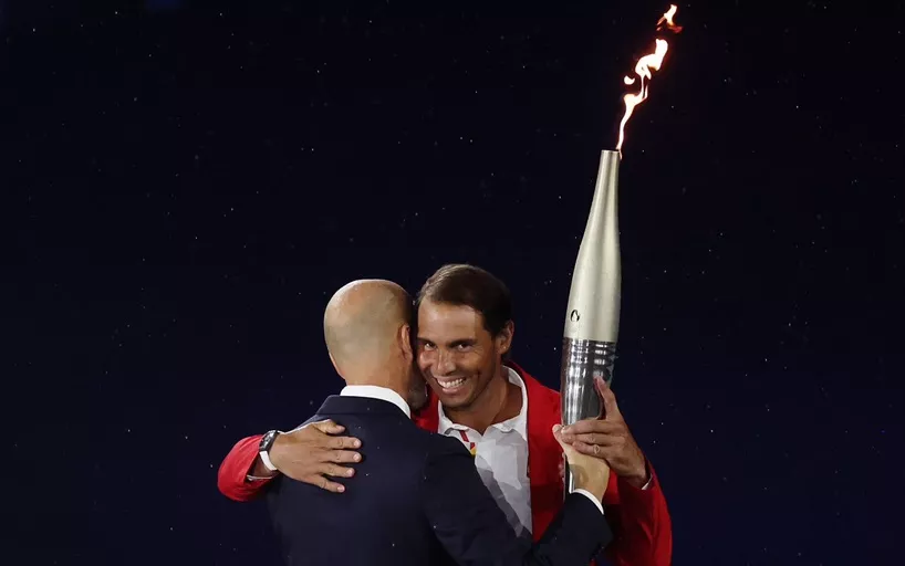 Rafa Nadal recibe la antorcha olímpica de manos de Zidane en uno de los últimos relevos antes de encender el pebetero.